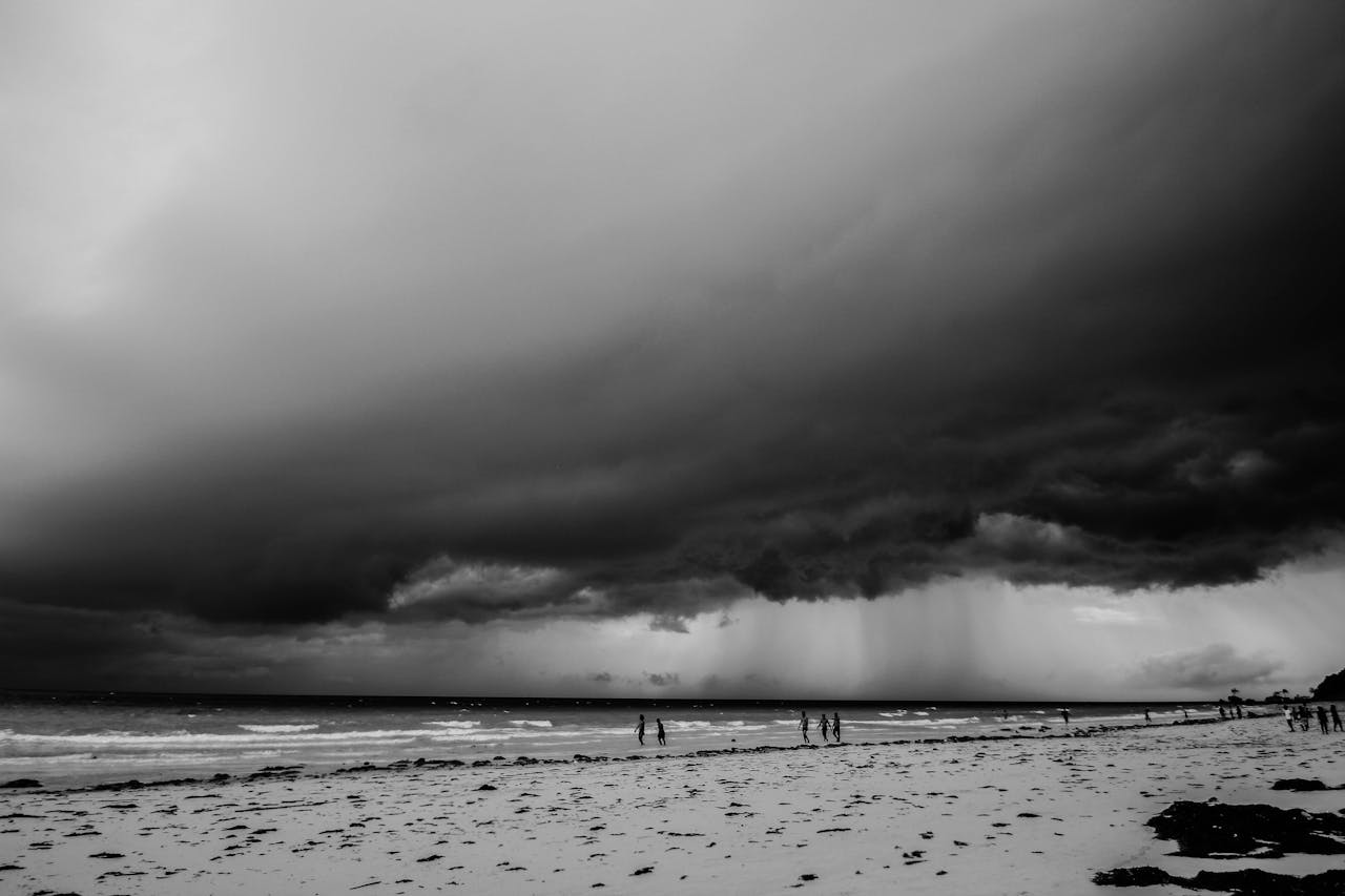 Black and white image of storm clouds rolling in over a beach.